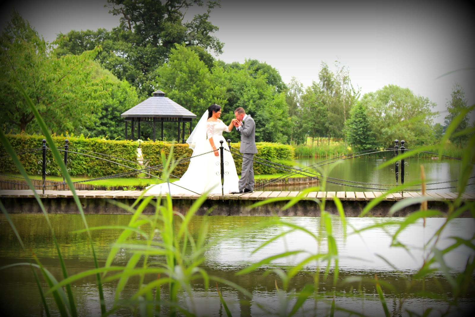 A bride and groom on a lakeside bridge at a Coventry-area wedding venue